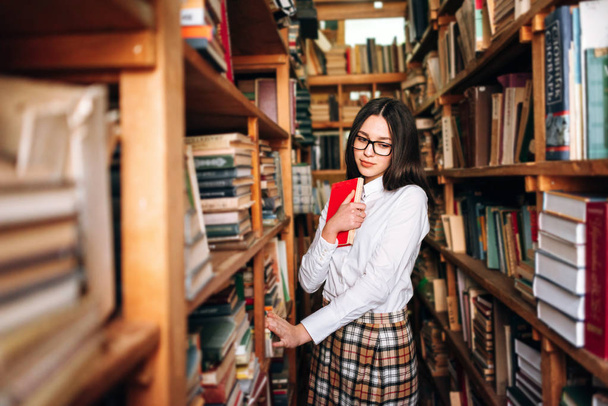 Ragazza adolescente che sceglie libri in biblioteca
 - Foto, immagini