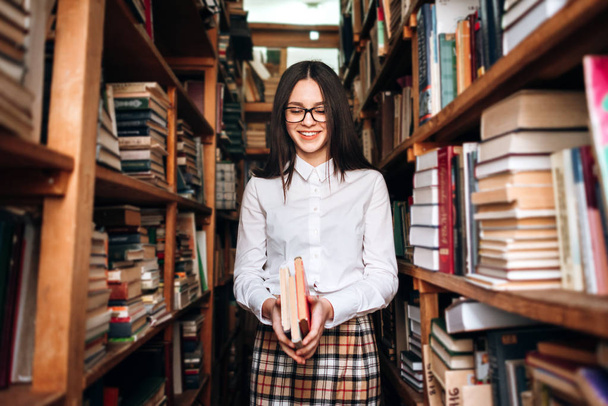 Nastoletnia dziewczyna wybiera książki w bibliotece - Zdjęcie, obraz