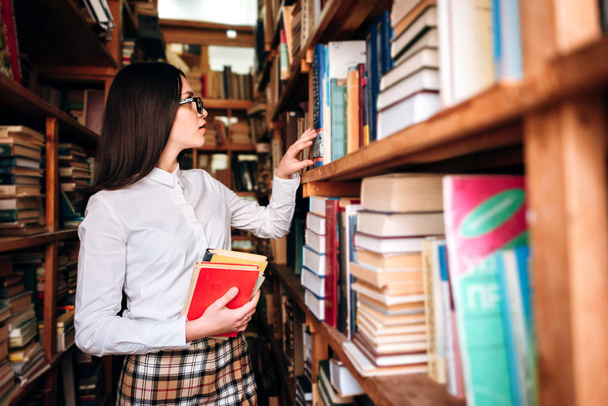 Девочка-подросток выбирает книги в библиотеке
 - Фото, изображение