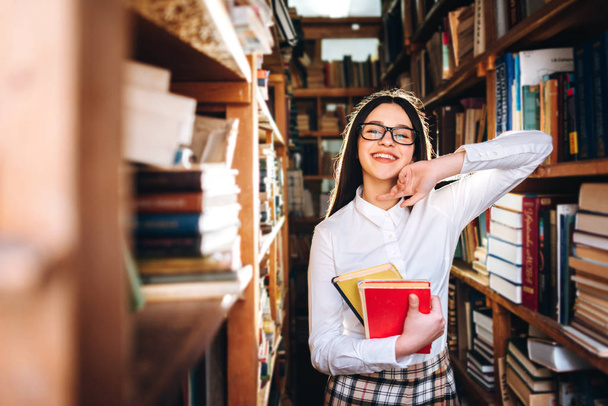 Aranyos tizenéves lány pózol a könyvtárban - Fotó, kép
