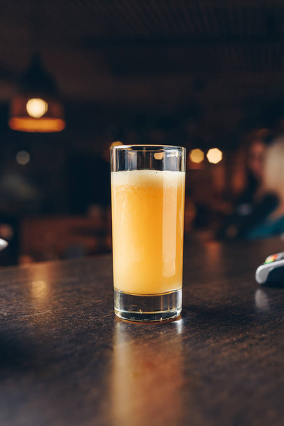 szklanka z pomarańczowym koktajlem na stole - Zdjęcie, obraz