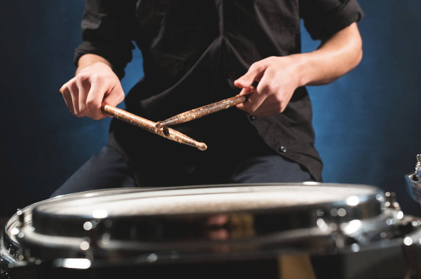 Close-up of a male drummers hand holding drum sticks while sitting behind a drum set - Photo, image