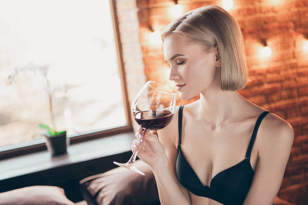 Close up side profile photo overjoyed beautiful tenderness gorgeous she her lady hold arms hands alcohol beverage glass eyes closed romance date sit sheets honeymoon bikini boudoir room indoors - Foto, immagini