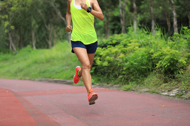 Фитнес спортивная бегунья бегает на открытой беговой дорожке в парке
 - Фото, изображение