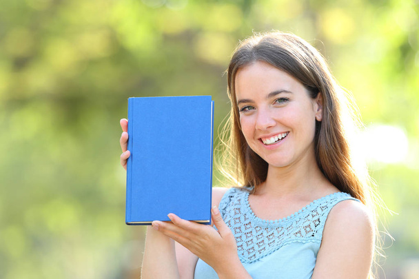 Happy woman showing a blank book cover - Foto, afbeelding
