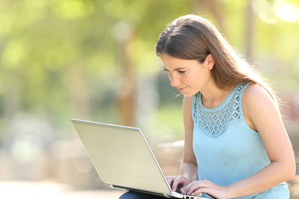 Femme sérieuse assise dans un parc en utilisant un ordinateur portable
 - Photo, image