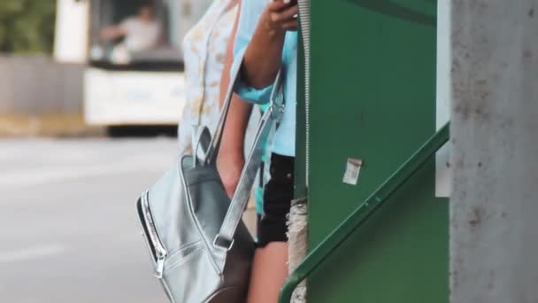 eine junge Frau zückt ihr Handy und blickt auf den Bildschirm - Filmmaterial, Video