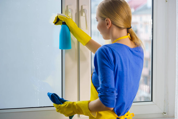 Жінка прибирає вікно вдома
 - Фото, зображення