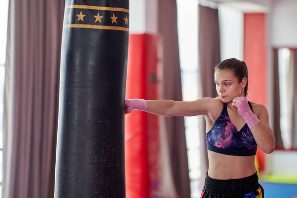 Kick-boxer female training at heavy bag with her hands wrapped - Valokuva, kuva