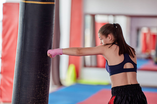 Kick-boxer female training at heavy bag with her hands wrapped - Foto, Imagen