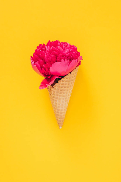 Flat lay Ice Cream Cone with pink peony on yellow background, copy space - Photo, Image