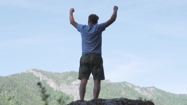 Człowiek podnosi ręce się stojący z powrotem na szczycie góry rano słońce połysk powolny ruch.  - Materiał filmowy, wideo