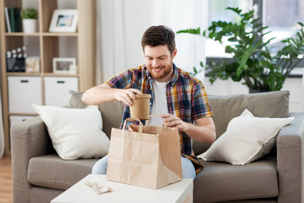 smiling man unpacking takeaway food at home - Fotó, kép