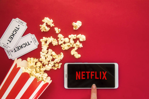 Ufa, Russia - Jule 7, 2019: Table with popcorn bottle and Netflix logo on smartphone. Netflix is a global provider of streaming movies and TV series. - Photo, image