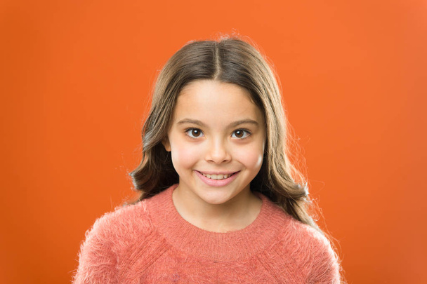 Wellbeing and health. Radiating happiness. Smiling child close up. Facial care. Cosmetology beauty concept. Girl child cute face orange background. Happy childhood. Child care and psychology - Fotografie, Obrázek