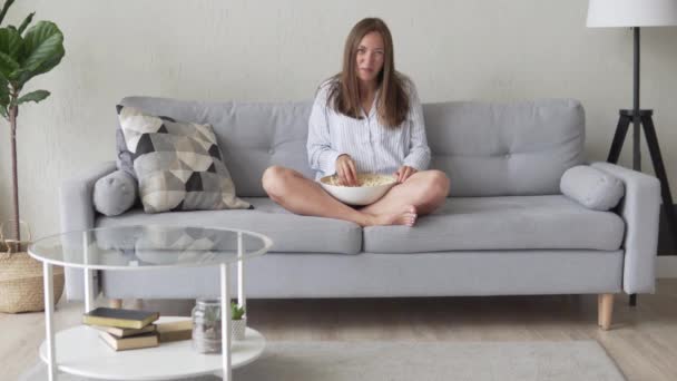 Fiatal nő tévénézés otthon a kanapén reggel - Felvétel, videó