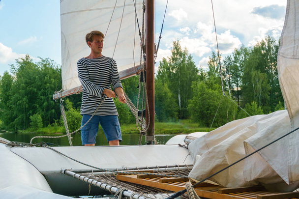 young sailor raises sail on a small sailing catamaran - Foto, imagen