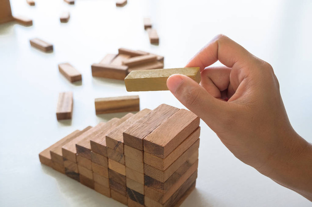 Cerca de mano sosteniendo bloques juego de madera. Riesgo de gestión y plan estratégico
 - Foto, imagen