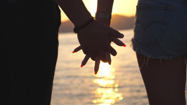 Силуэт мужских и женских рук, держащих друг друга на закате на морском фоне. Молодая пара, соединяющая руки снаружи. Понятие любви и счастья. Закрыть задний обзор Медленное движение - Кадры, видео