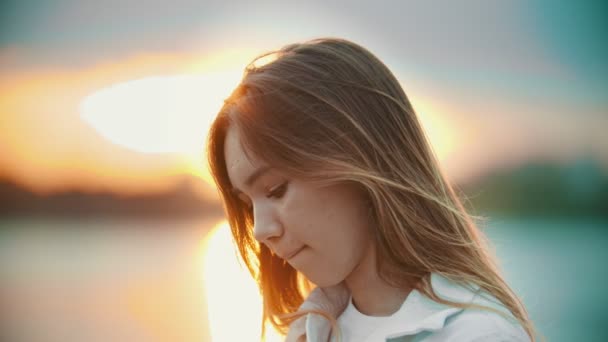 Een tiener meisje met licht bruin op zoek naar beneden-zonsondergang - Video