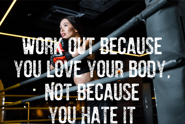 low angle view of attractive woman in boxing gloves standing in sports center with work out because you love your body, not because you hate it illustration - Foto, Imagem