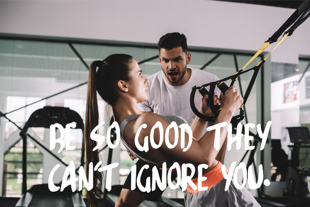 excited trainer shouting while motivating sportswoman pulling up on suspension trainer near illustration with be so good they cant ignore you inscription - Photo, Image