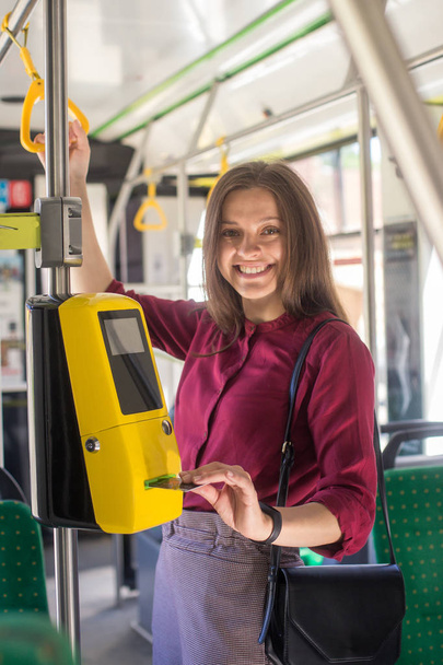 Female Woman paying conctactless with smartphone for the public transport in the tram. Yellow ticket machine in the modern tram - Zdjęcie, obraz