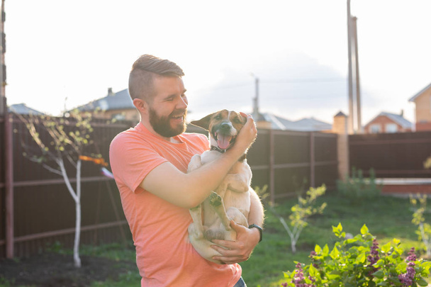 Eläinten, lemmikkieläinten ja ihmisten käsite - hymyilevä mies rento persikka väri t-paita hänen jack russell terrieri
 - Valokuva, kuva