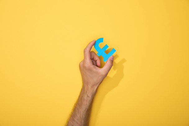 visão cortada do homem segurando libra de papel azul no amarelo
 - Foto, Imagem