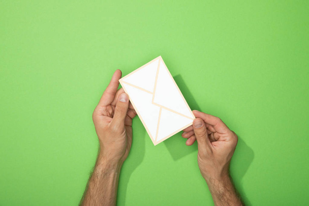 vista cortada do homem segurando ícone de papel de envelope no verde
 - Foto, Imagem