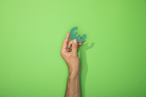 vista cortada do homem segurando ícone de papel do sinal de moeda do euro no verde
 - Foto, Imagem