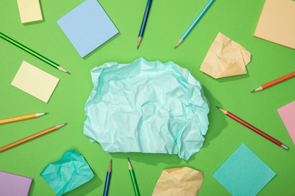 top view of scattered pieces of crumpled paper near pencils on green - Fotografie, Obrázek