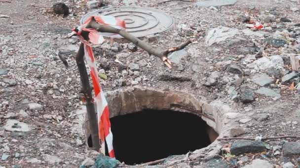 Warning red-and-white tape fencing over the open well sewer manhole. - Footage, Video