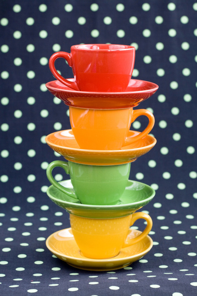 Quatre tasses colorées sur un fond sombre s taches vertes
 - Photo, image