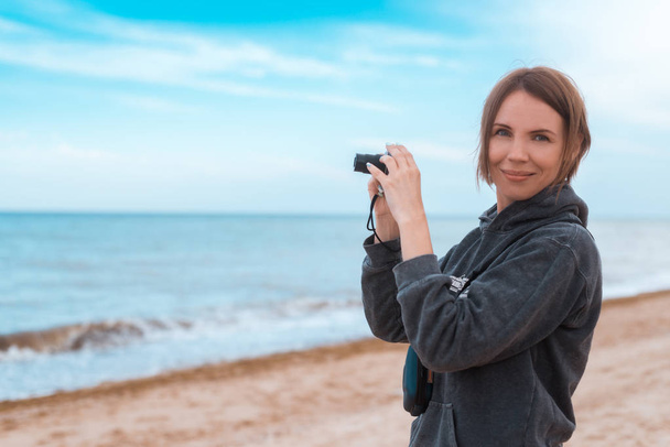 Žena průměrných let dělá fotku na pobřeží, oceán. - Fotografie, Obrázek