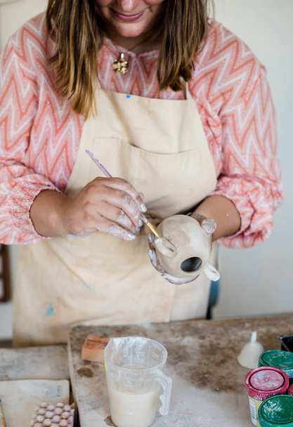 Lady ceramic artist working in her studio interior, womans hands painting objects - Photo, Image