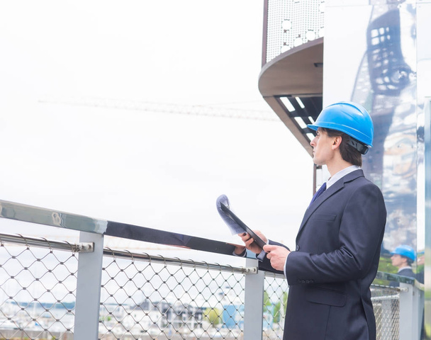 Real estate developer in helmet. New office construction. Confident businessman or architect in front of modern office building. - 写真・画像