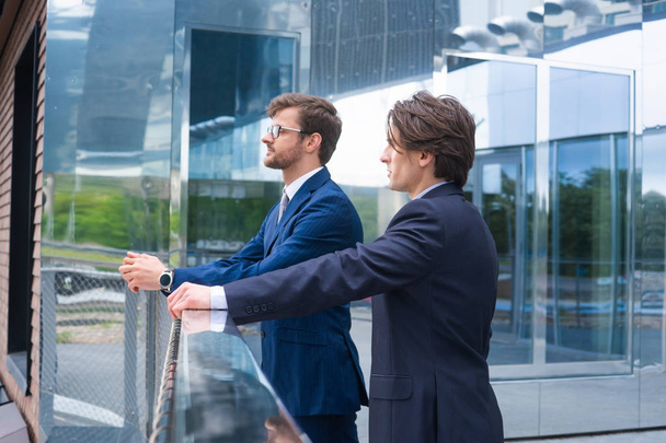Confident business men talking in front of modern office building. Businessman and his colleague. Banking and financial market concept. - Fotó, kép