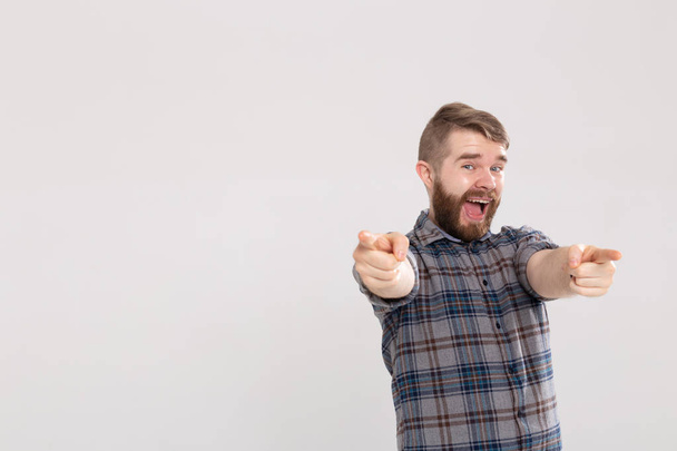 Jeune homme excité avec barbe, doigt pointant vers la caméra sur un fond blanc avec espace de copie
 - Photo, image