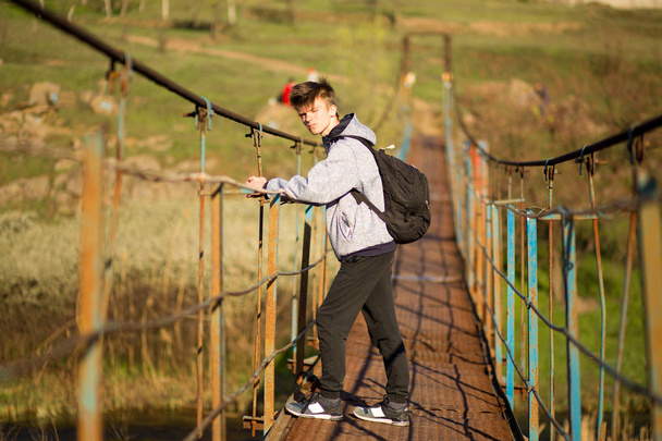 川の上に良い晴れた日に吊り橋を渡る旅行男 - 写真・画像