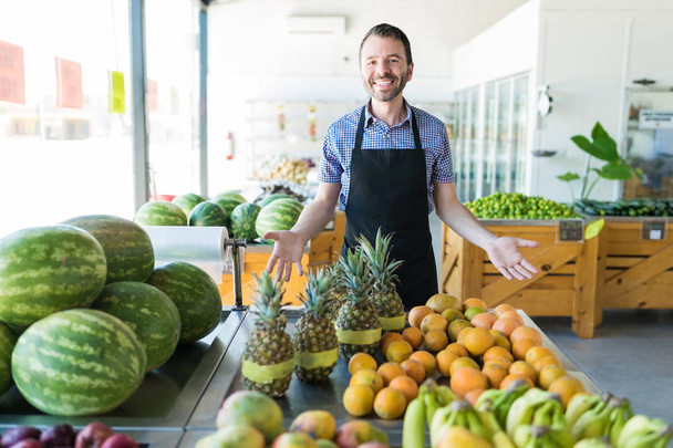 Caucasiano proprietário do sexo masculino promovendo várias frutas orgânicas nutritivas na loja
 - Foto, Imagem