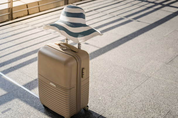 maleta con sombrero de verano en la sala de salida del aeropuerto, viaje y concepto de vacaciones
 - Foto, Imagen