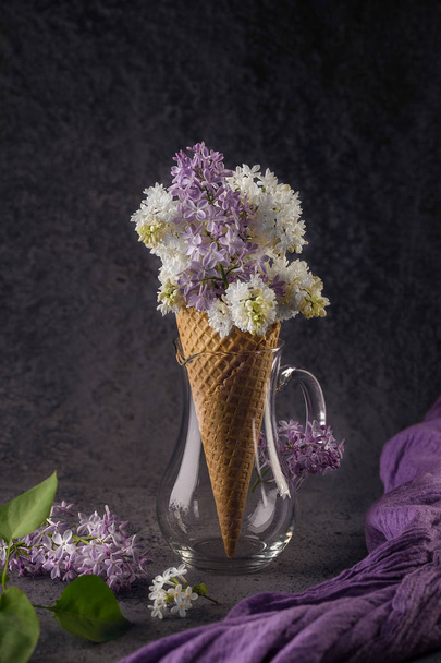 Waffle cone with purple and white lilac on dark gray background - Fotoğraf, Görsel