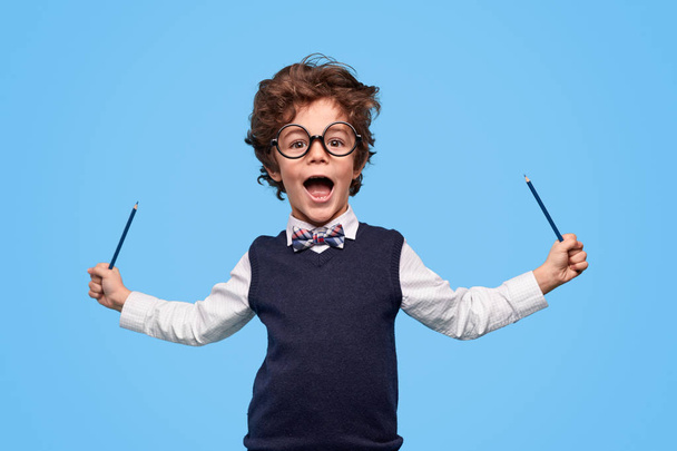 Excited schoolboy having fun with pencils - Foto, imagen