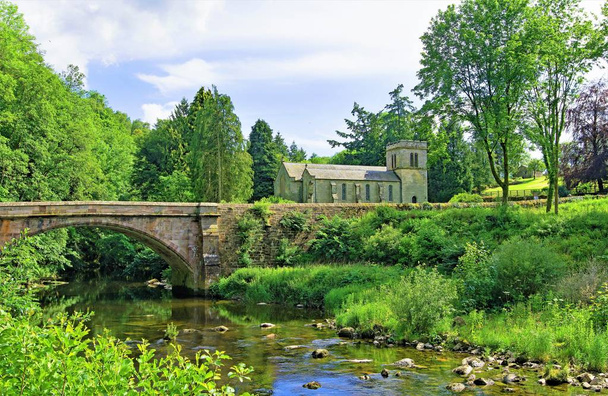 Het veroveren van een typisch Engels dorp pastorale scène, met inbegrip van Askham brug en St Peter's Church, in Askham, Penrith, Cumbria, Engeland. - Foto, afbeelding