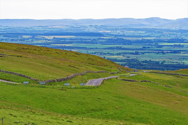 Einfangen eines nebligen und atmosphärischen Fernhorizonts, mit saftigen Wiesen und Ackerland im Vordergrund, in der Nähe von Penrith, in Cumbria, England. - Foto, Bild