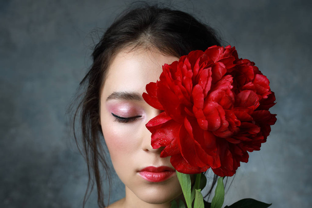 Beautiful fresh Asian woman with red peony and red lipstick - 写真・画像