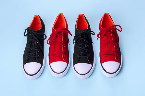 Новые красные и черные кроссовки на синем фоне с копировальным пространством
. - Фото, изображение