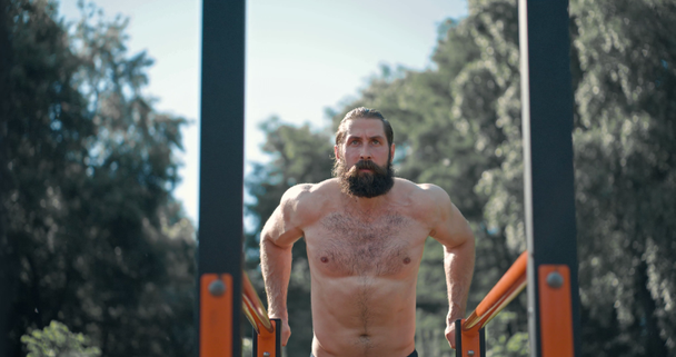 Muscular bearded man workout, outdoor Fitness parallel bars slow motion 4K - Felvétel, videó
