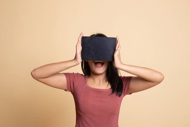 Young Asian woman with a computer tablet over her face. - Foto, Imagen